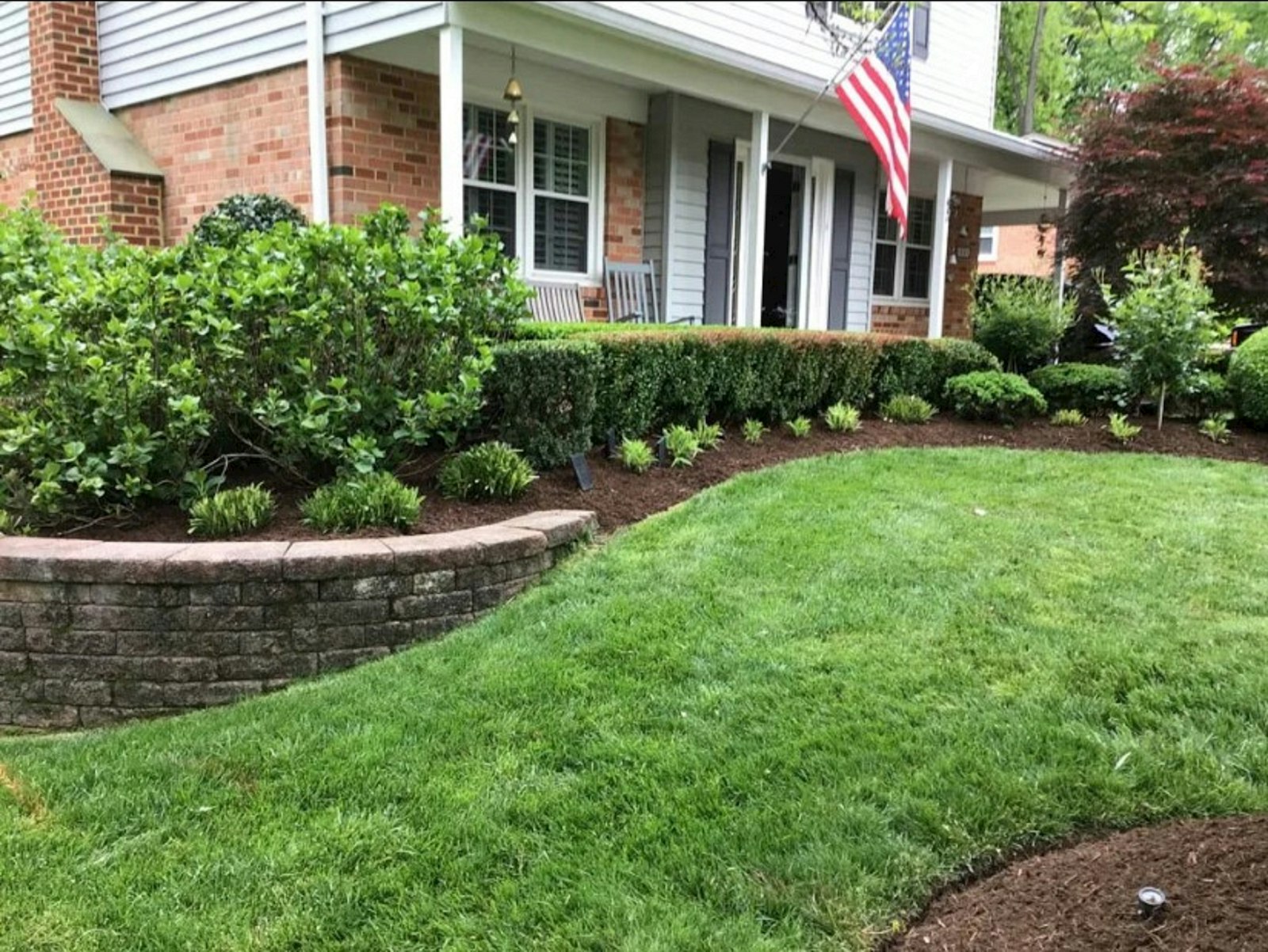 Freshly mowed front lawn with crisp mulch bed edges in front of a brick two-story house